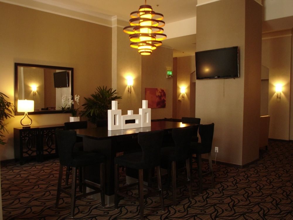 Dining area with table and chairs, TV, and decorative elements in a hotel.