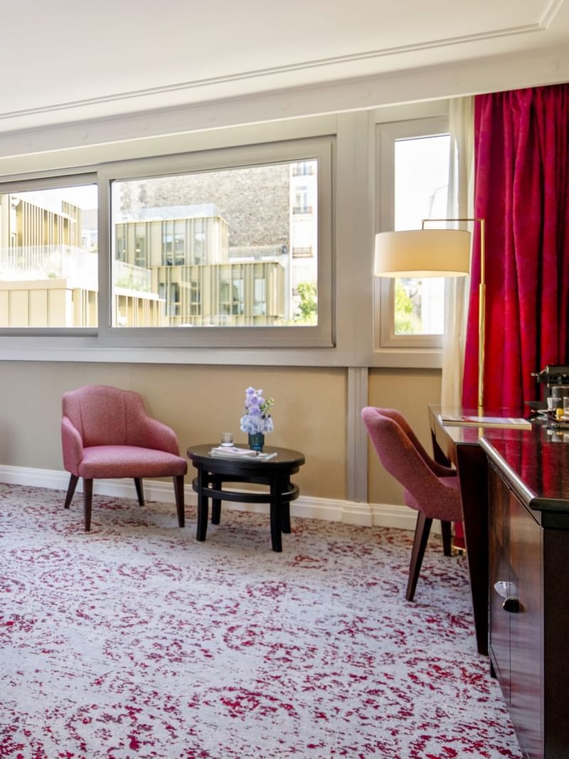 Marble vanity by a bathtub near a bedroom area with a pink chair and desk in Deluxe Room at Warwick Paris Champs Elysées