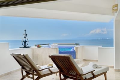 Balcony with ocean view, two lounge chairs, a small hot tub, and a decorative candle stand.