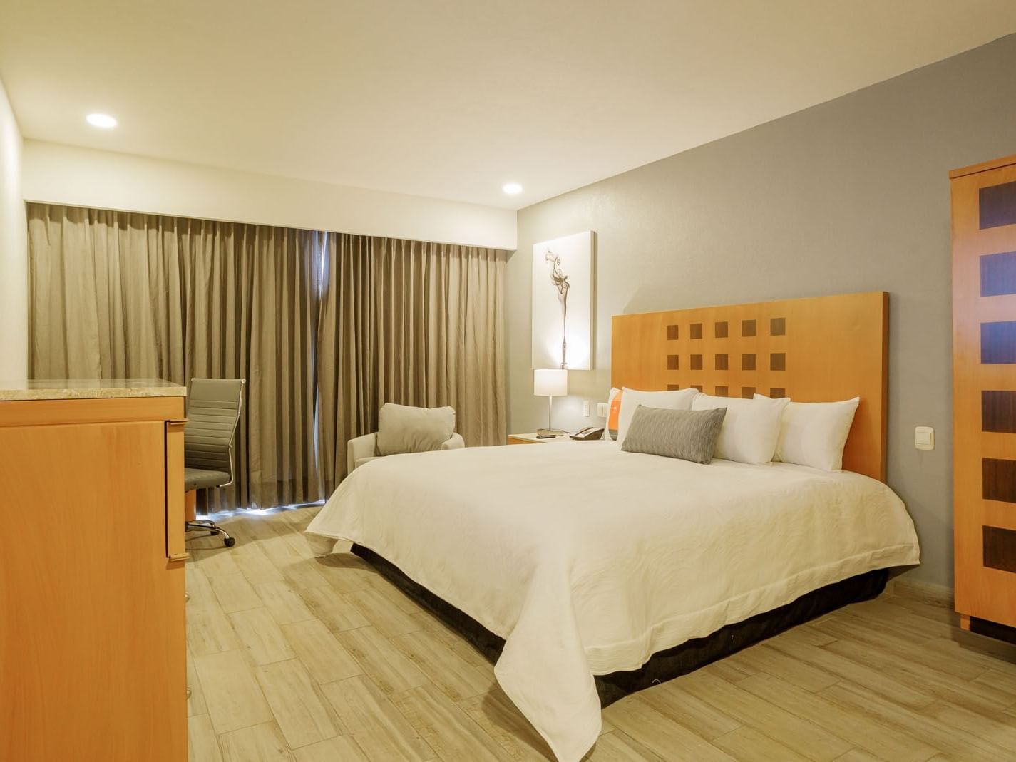 King Deluxe Superior room with white linens, wooden furniture, and neutral-toned curtains at Real Inn Torreon