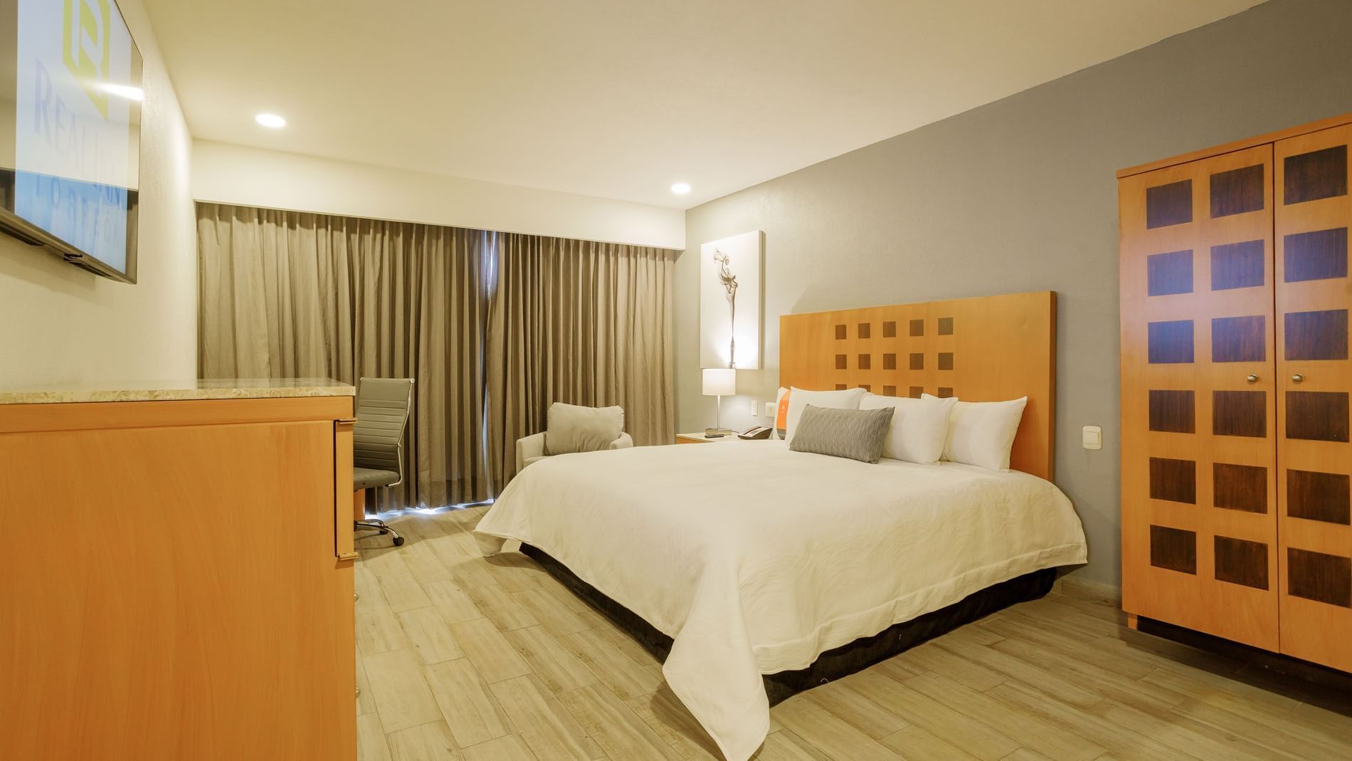 King Deluxe Superior room with white linens, wooden furniture, and neutral-toned curtains at Real Inn Torreon