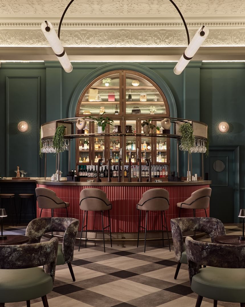 Elegant Gott\'s Bar with plush seating and arched shelving, featuring exposed bottles at The Met Hotel Leeds, England