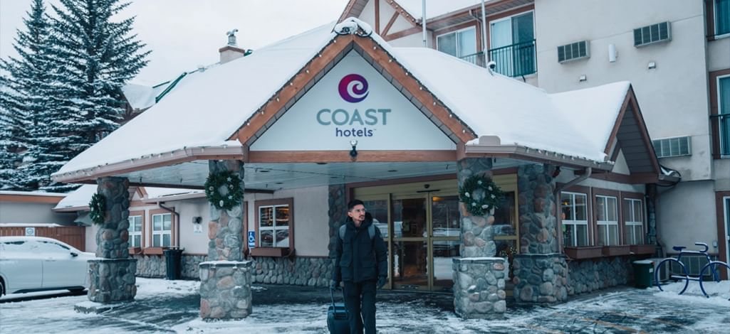 Guest arriving at Coast Hotels in Canmore during winter, featuring a snowy entrance with festive decorations and a welcoming atmosphere.