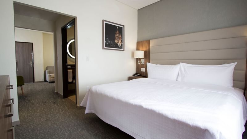 Modern room featuring a king-size bed and an adjoining sitting area at Fiesta Inn Suites Aeropuerto del Bajío