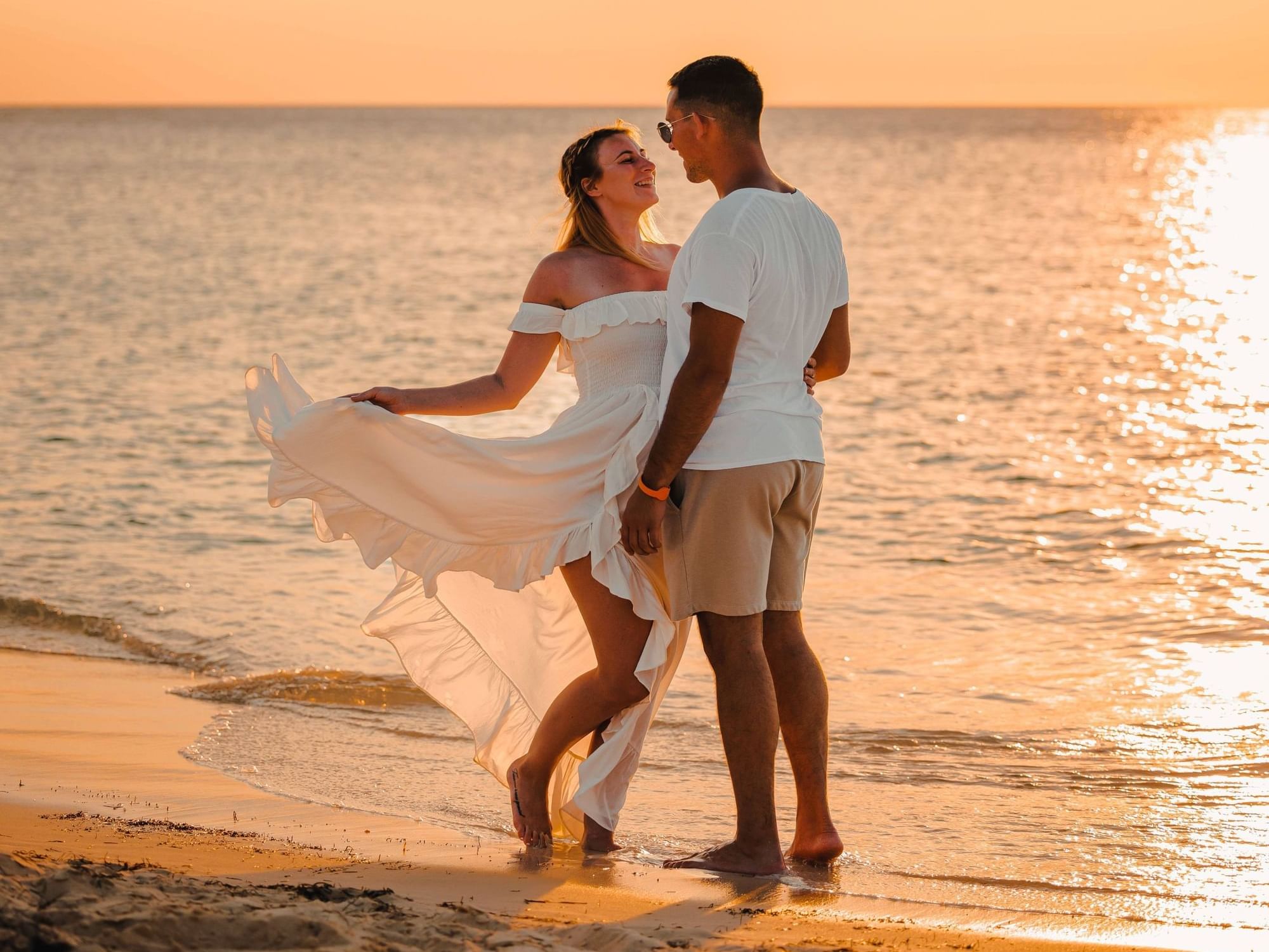 Couple posing by the beach at sunset featuring the Vow Renewal  package at Passions on the Beach