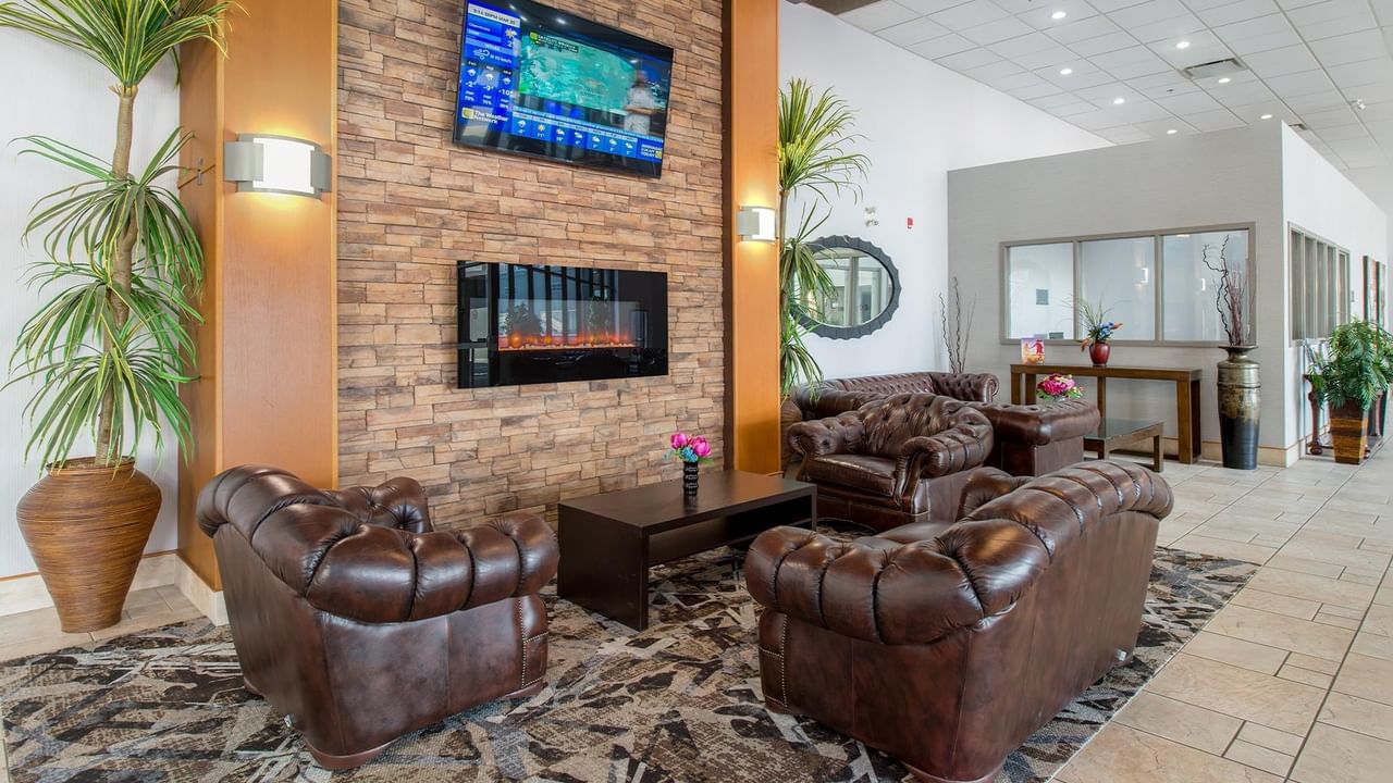 Lobby with couches, fireplace, TV, and plants at Coast Lethbridge Hotel & Conference Centre.