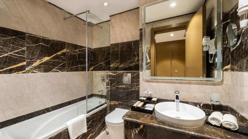 Bathroom of Deluxe Room with vanity, bathtub and lavatory at Warwick Riyadh