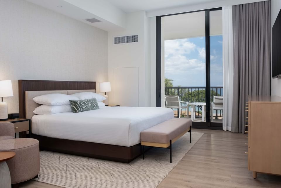 TV facing bed with ottoman by the window in Kai Ocean View Ali'i Suite at Maui Coast Hotel