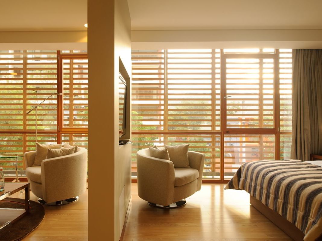 Junior Suite espaçosa com janelas amplas, área de estar com poltronas bege e cama king no NOI Vitacura em Vitacura.