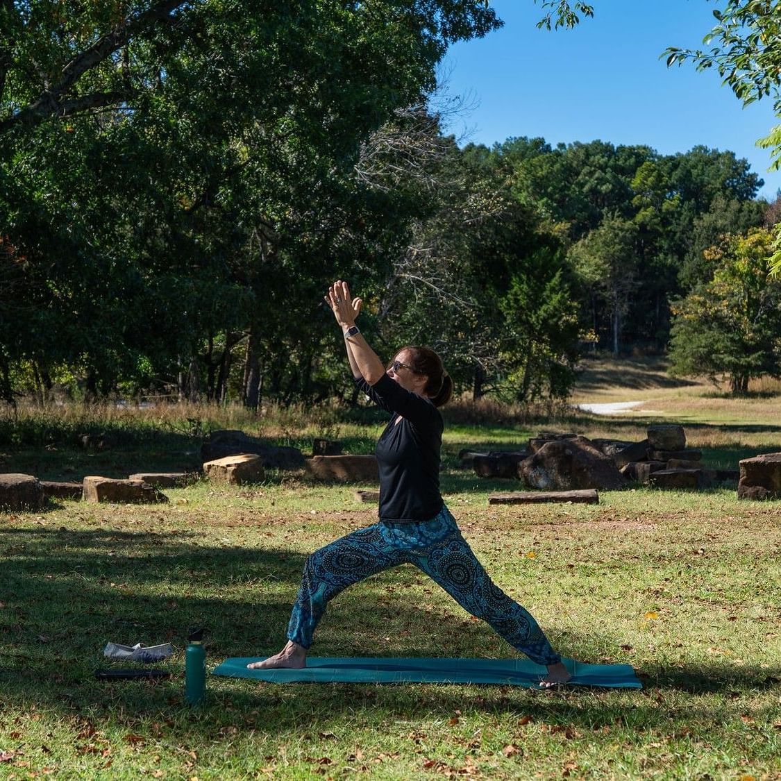 Woman performing yoga pose on mat in grassy park during Slow Flow Yoga event.