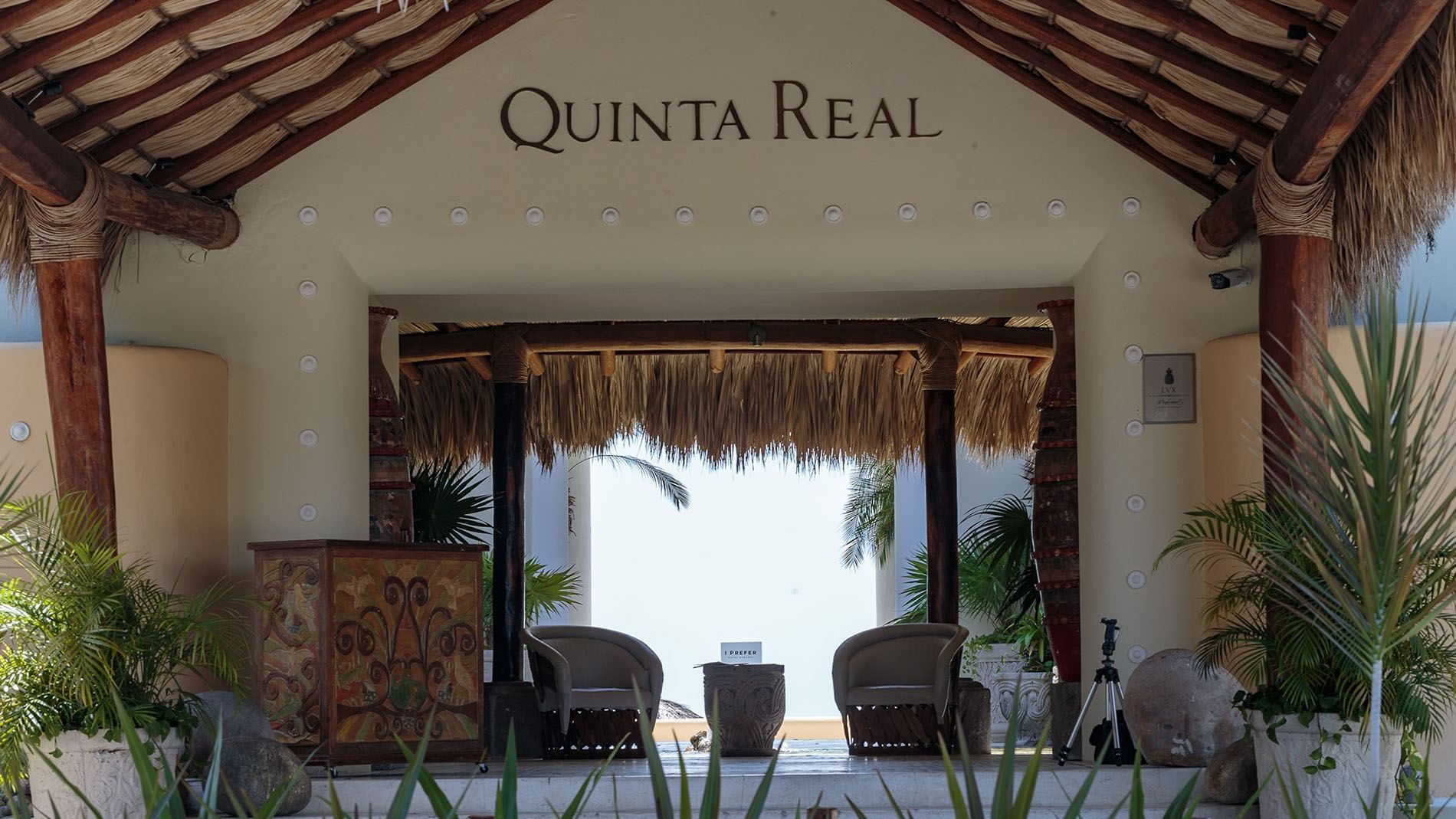 Main entrance featuring a thatched roof with armchairs under a stone arch at the beach at Quinta Real Huatulco