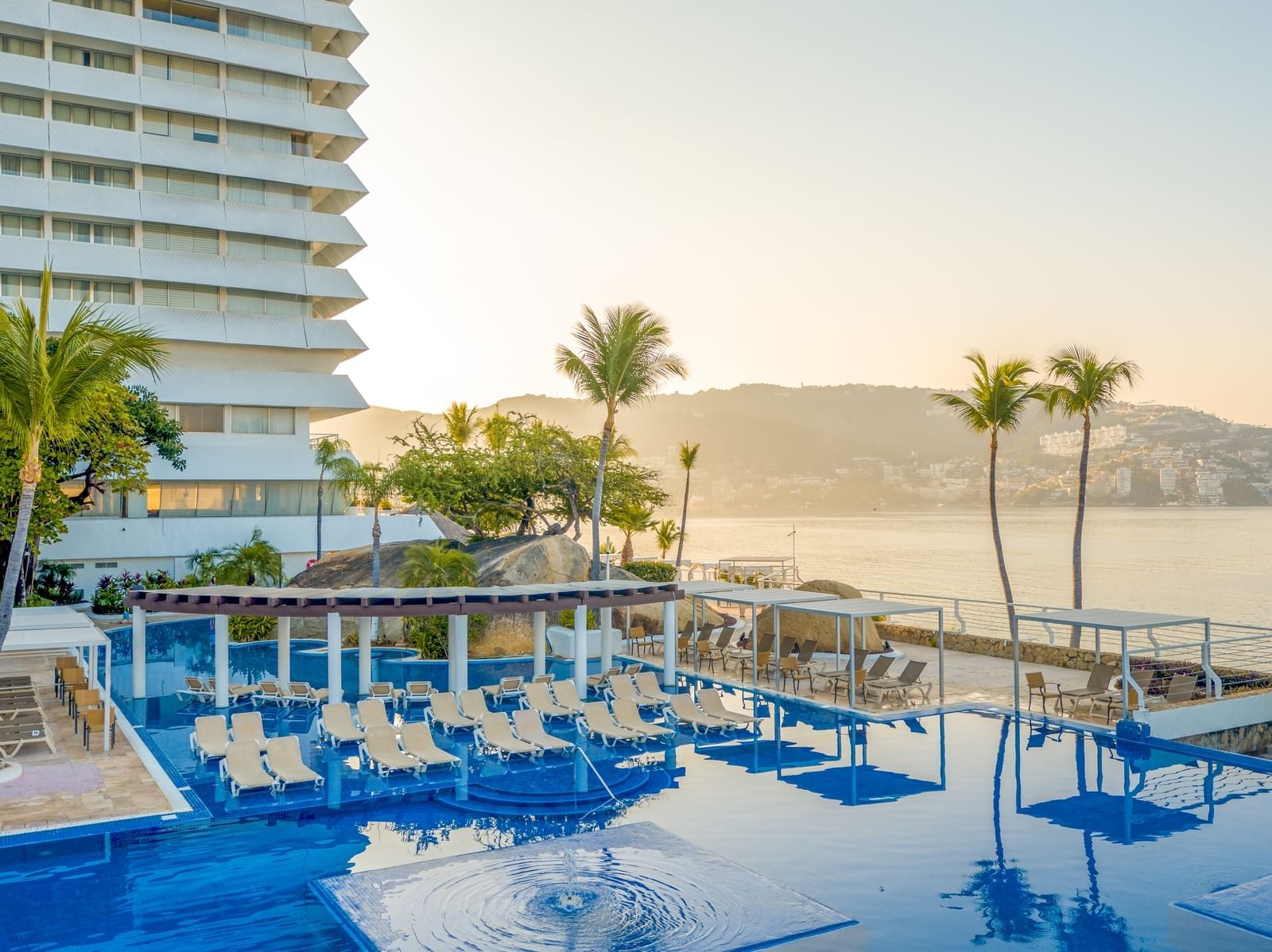 Tumbonas junto a la piscina al aire libre en FA Hotels & Resorts al atardecer