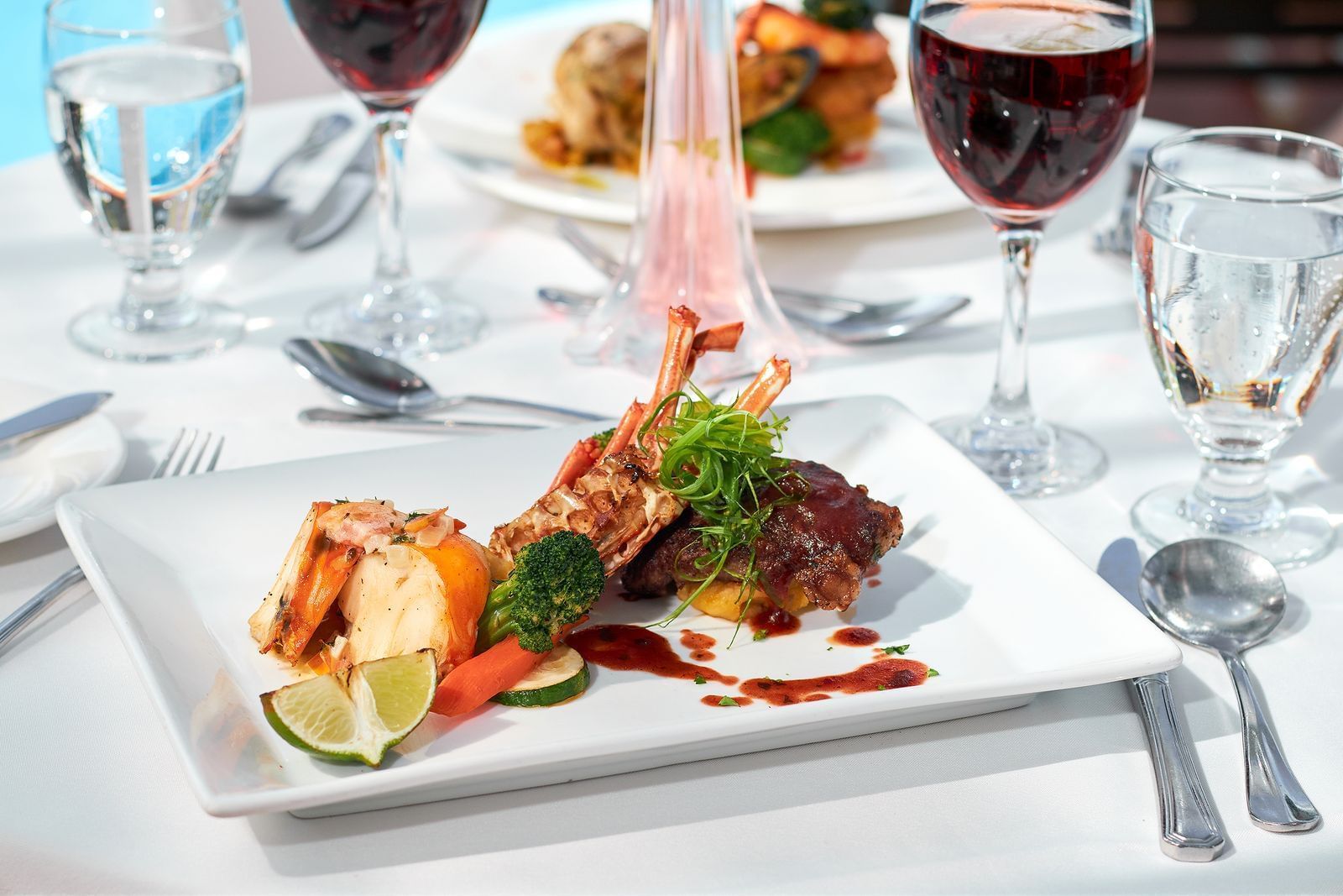 Dish with lobster tail, sweet potato mash, & steamed broccoli, served alongside wines at Spices Restaurant, Bay Gardens Hotel