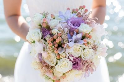 Close-up of a bridal bouquet with white and purple roses held by a bride at Spencer Hotel & Conference Centre