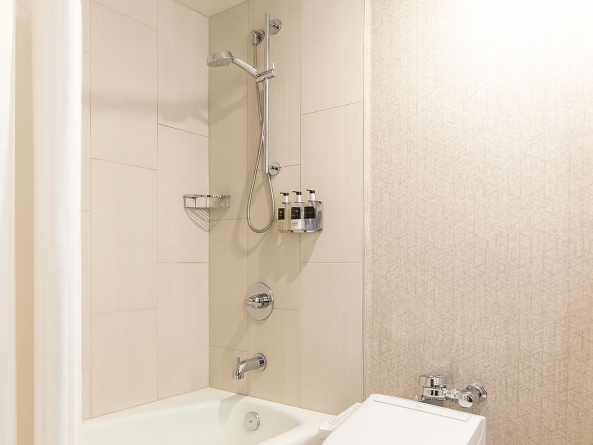 A hotel bathroom with a bathtub, removable shower head, and toilet.