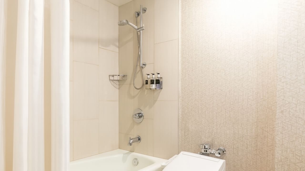 A hotel bathroom with a bathtub, removable shower head, and toilet.