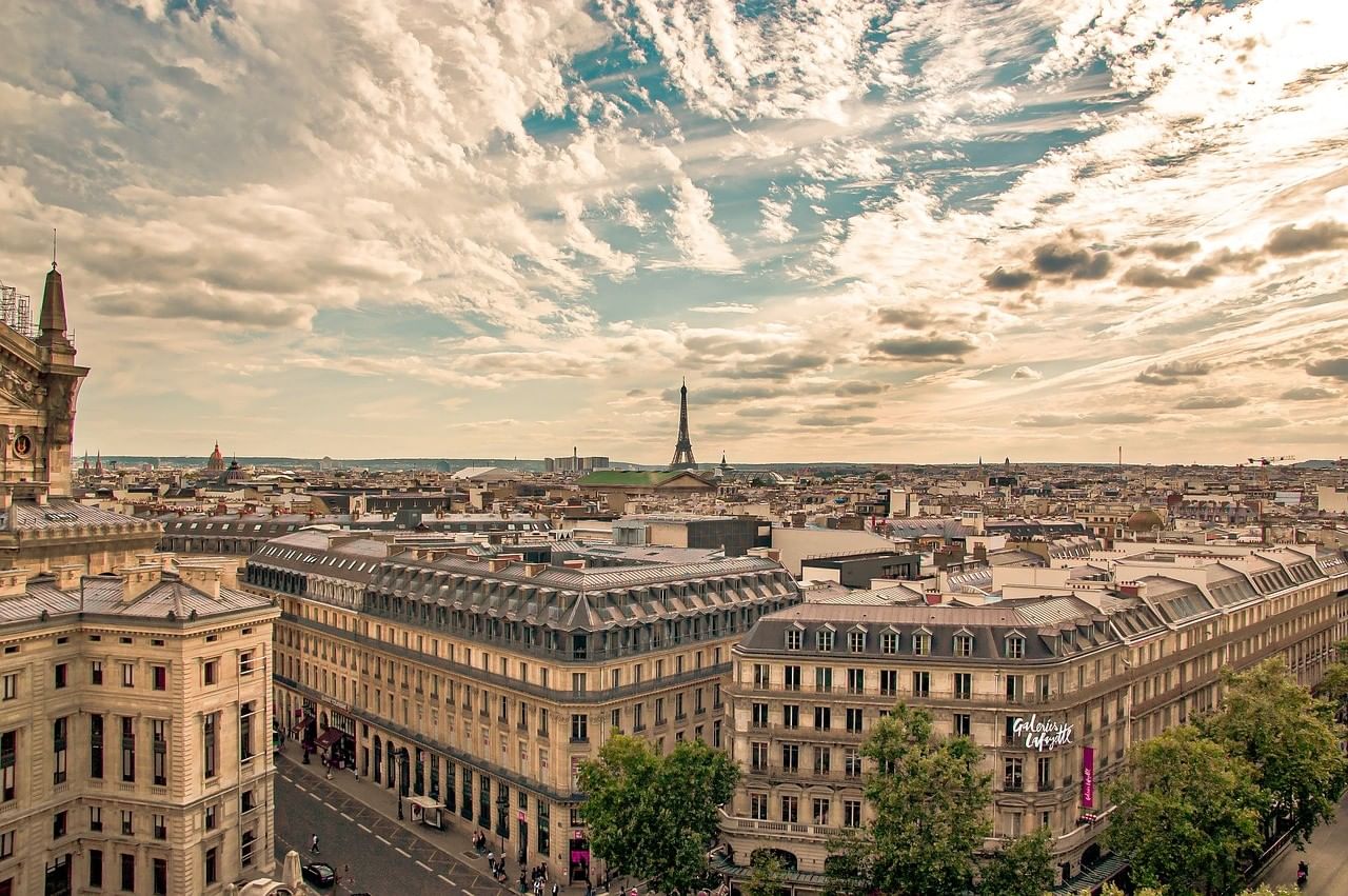 High-angle view of Parisian streets and classic architecture with the Eiffel Tower in the distance near ResidHotel