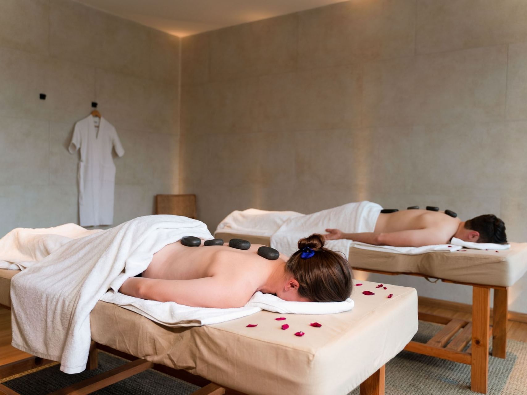 Two people receiving hot stone massages on spa beds with towels at The Terraces Resort & Spa