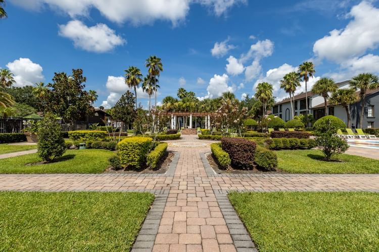 Brick walkway through manicured gardens with palm trees and resort buildings at Legacy Vacation Resorts