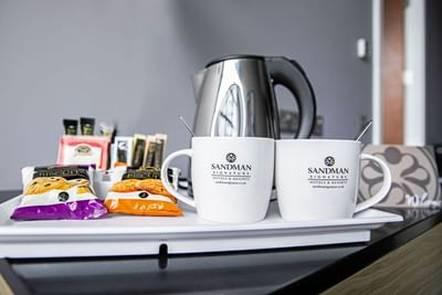 An image of a kettle, ingredients to make tea/coffee, spoons and