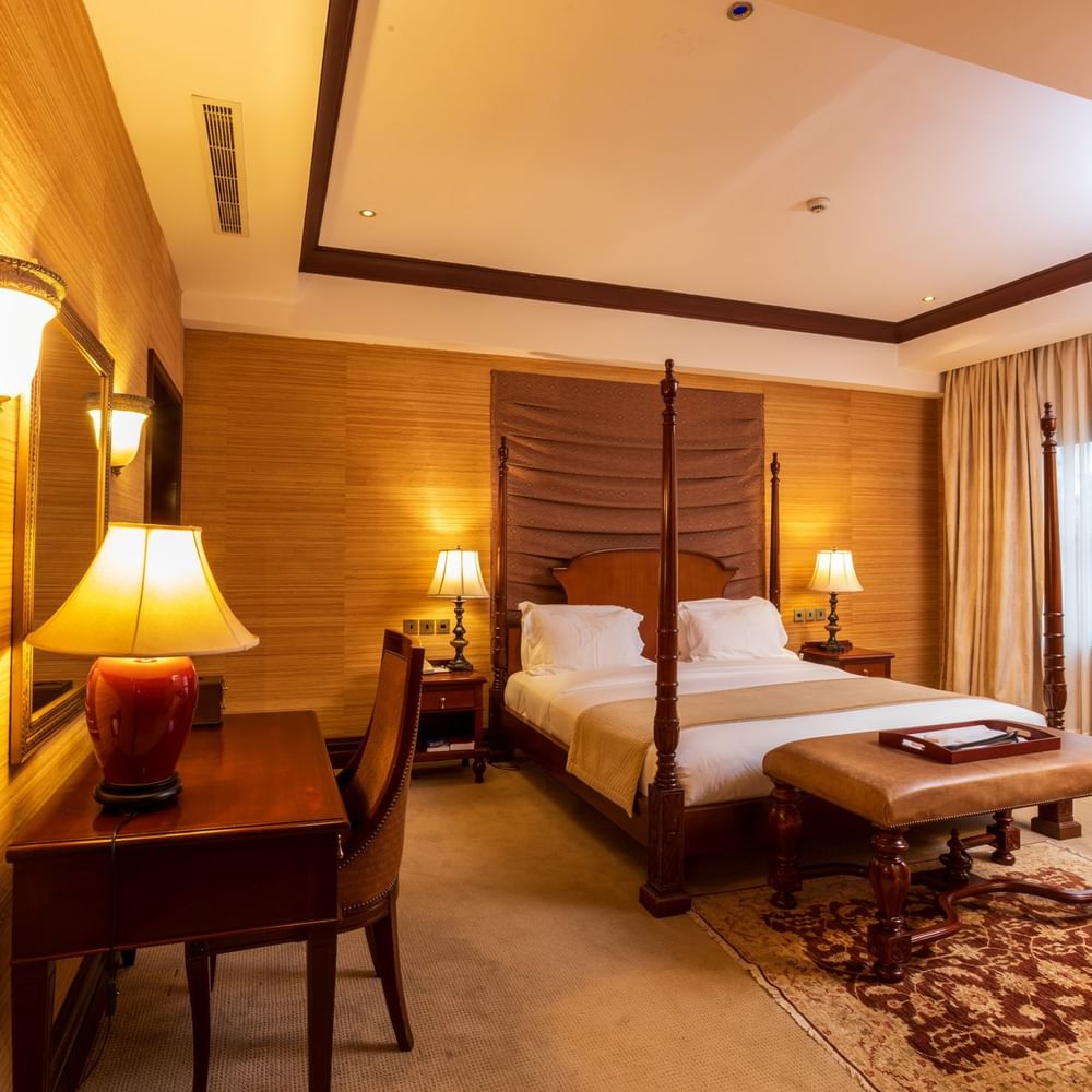 Elegant Presidential Suite with wooden decor and a four-poster bed at Lake Victoria Serena Golf Resort & Spa in Kampala.