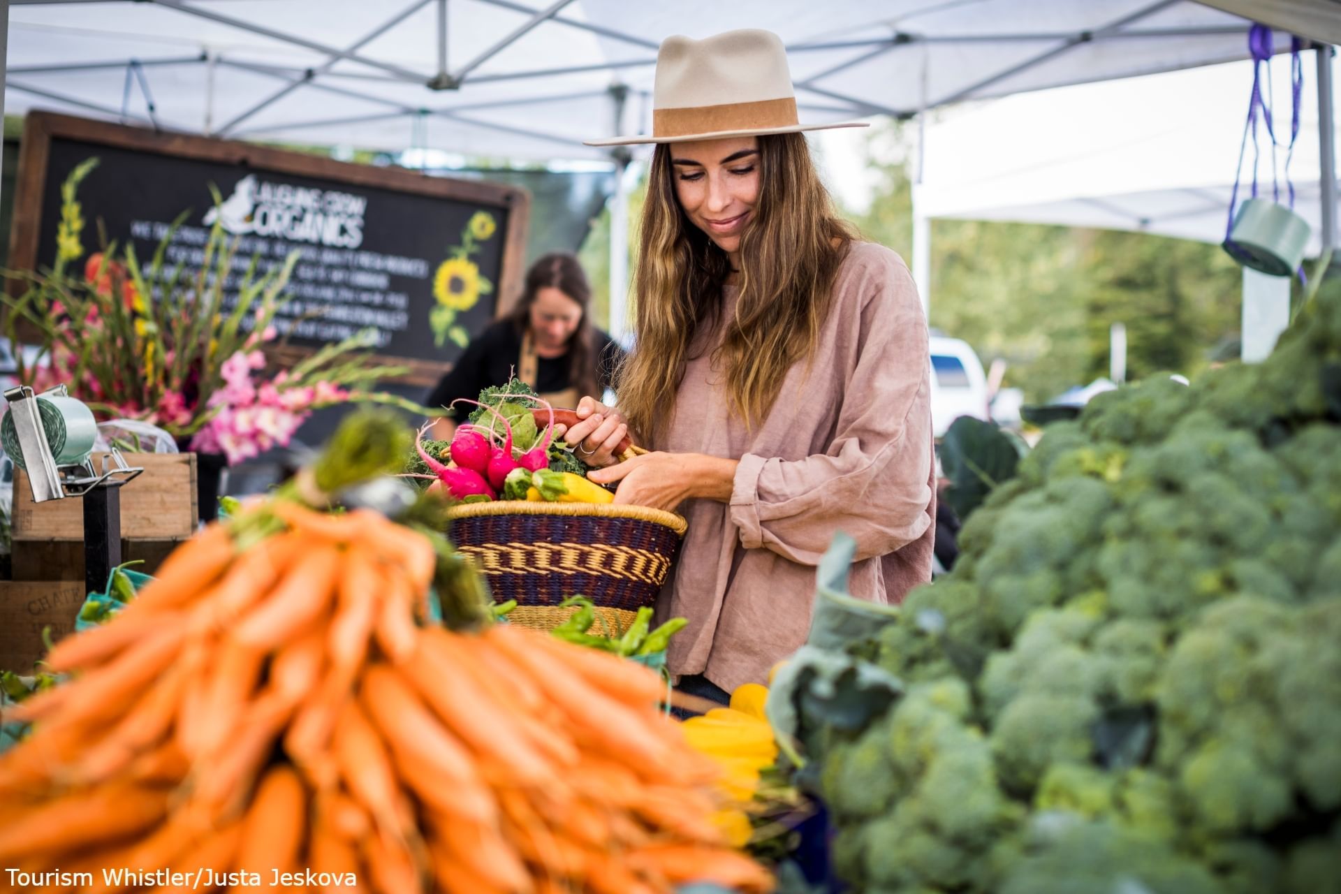 Woman by a veg stall in Whistler Farmers' Market near Blackcomb Springs Suites