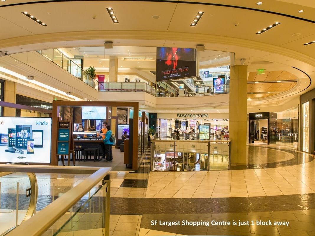 A shopping mall's interior with people and advertisements at Pickwick San Francisco.