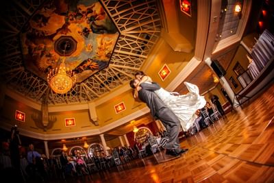 Newlyweds dancing in decadent ballroom.