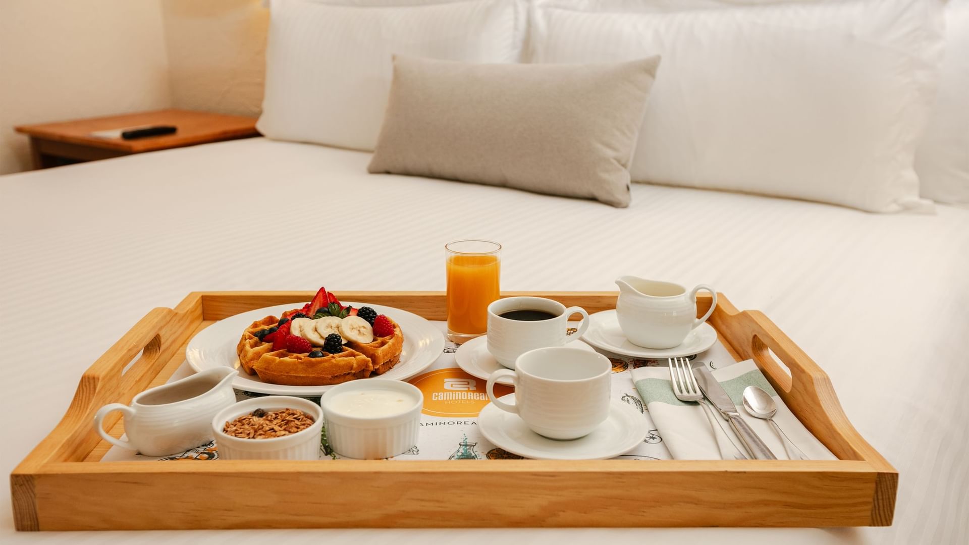 Tray with coffee, breakfast food, and fruit on a bed at Camino Real Guadalajara in Zapopan