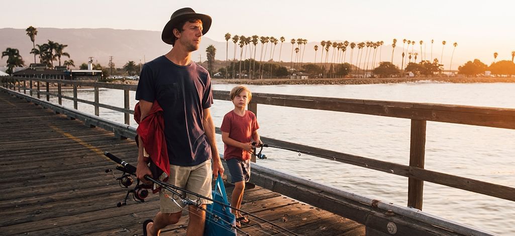 father and son on pier with fishing rods