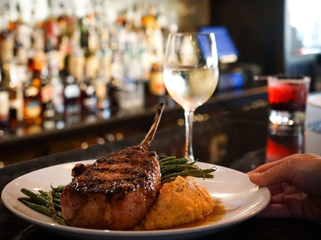 Grilled bone pork chop served with green beans & mashed potatoes served in Cora’s Restaurant and Bar near The Markham Hotel