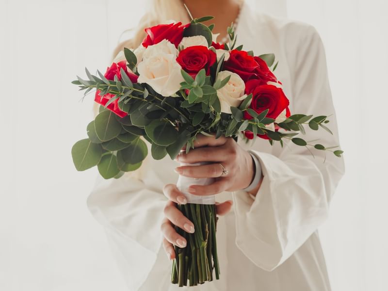 Woman holding red and white rose bouquet with green leaves at Fiesta Americana Riviera Nayarit Resort & Spa.