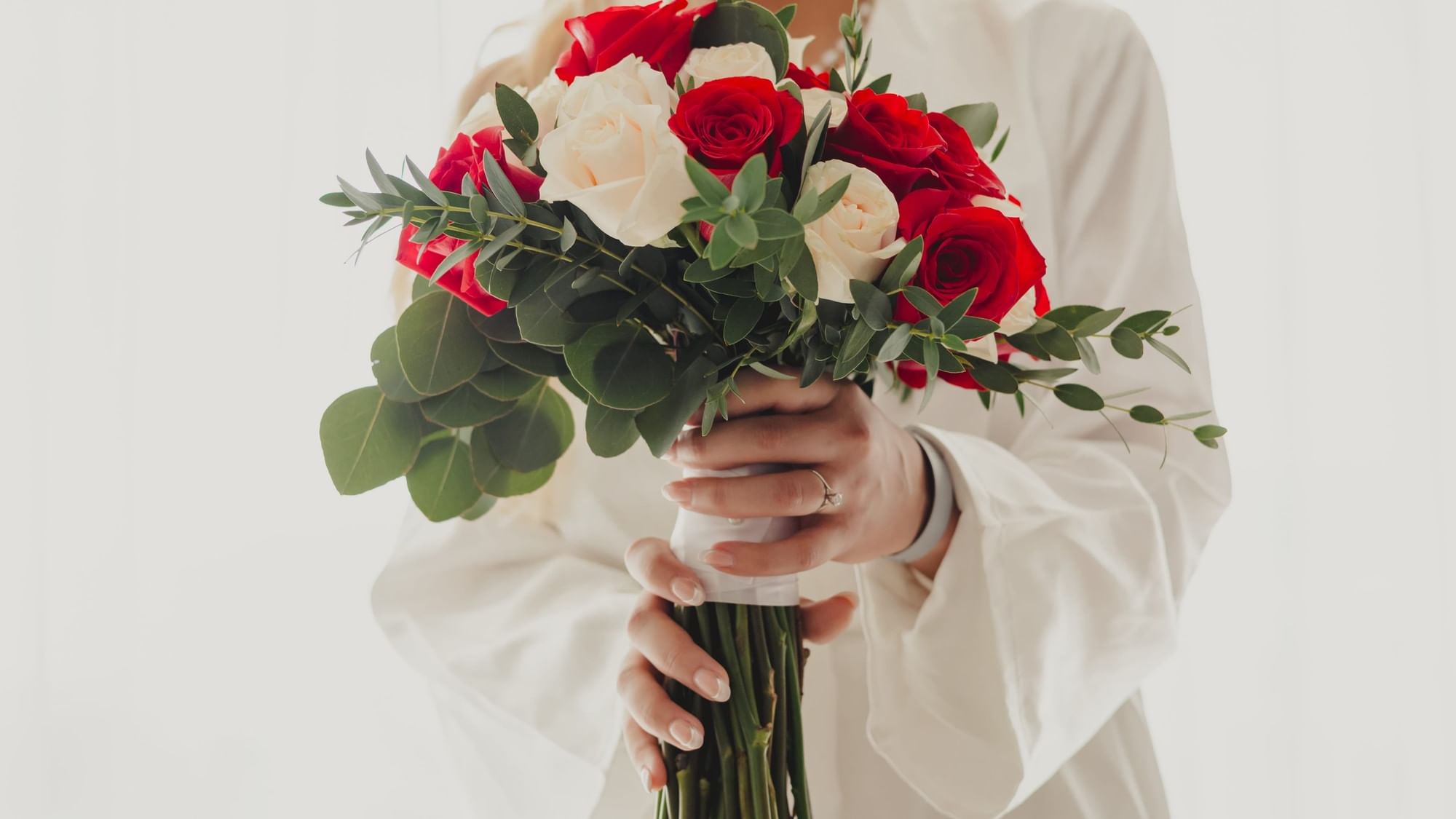 Woman holding red and white rose bouquet with green leaves at Fiesta Americana Riviera Nayarit Resort & Spa.
