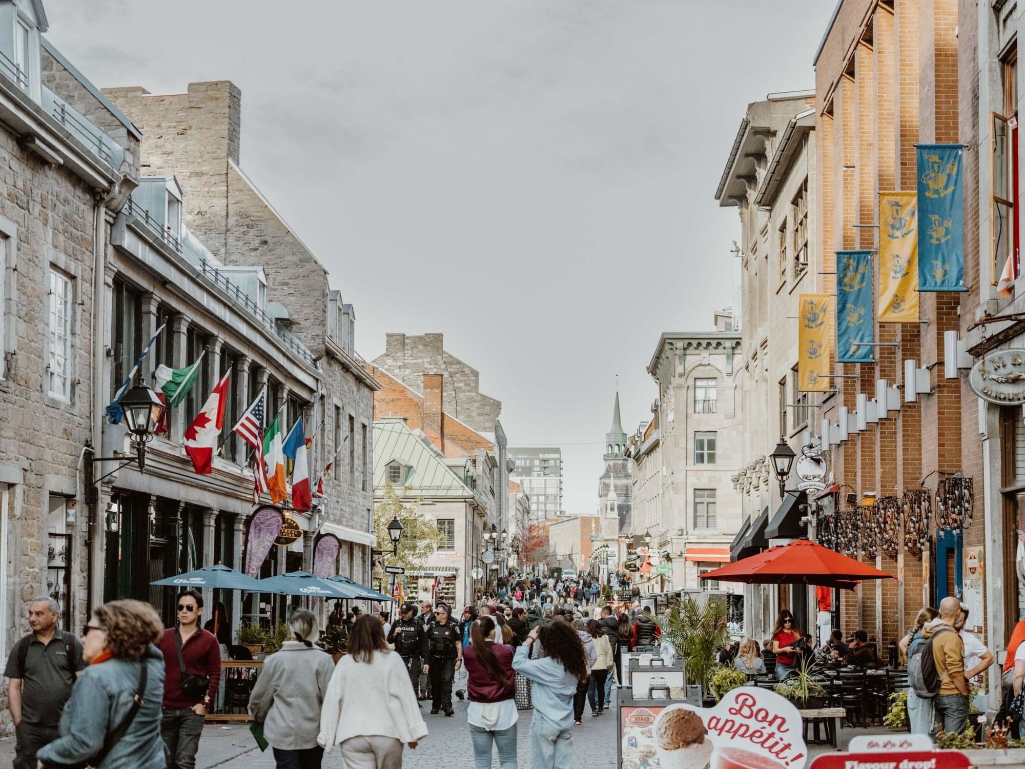 Rue animée au Vieux-Montréal avec de nombreux piétons et des bâtiments historiques.
