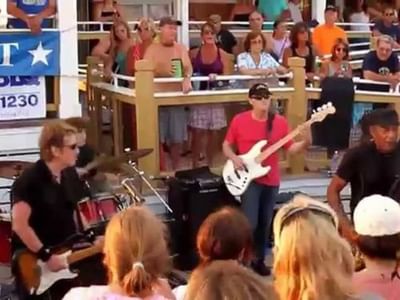 Outdoor concert with musicians playing instruments while the crowd enjoying the performance near Breezeway Boutique Hotel