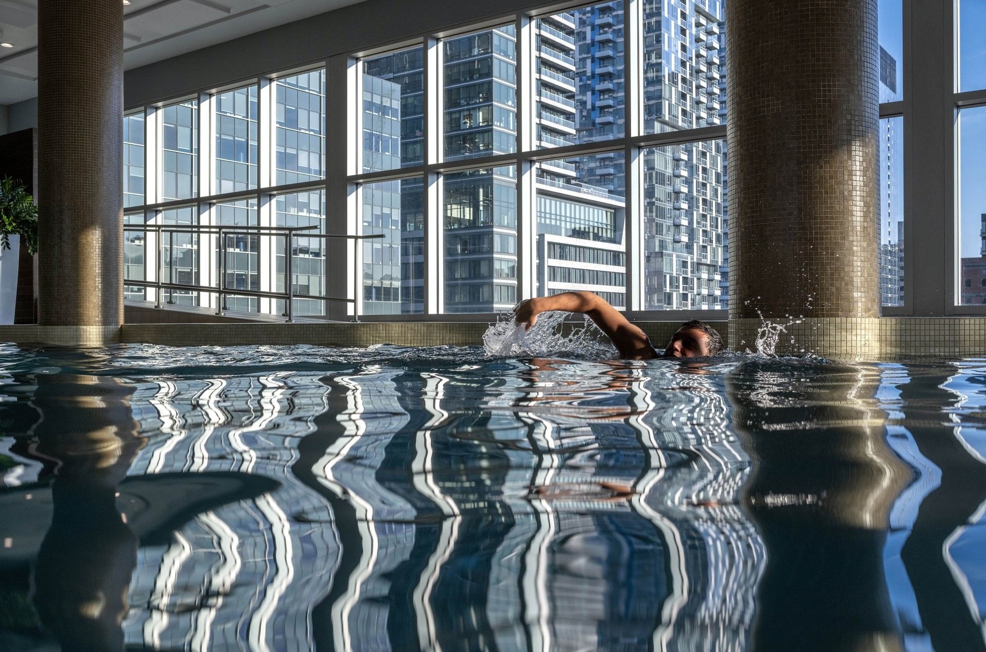 Nageur dans une piscine intérieure avec vue sur les gratte-ciel à Warwick Le Crystal Montreal