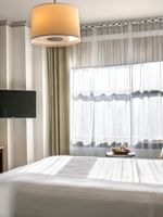 Wooden desk and chair near windows with sheer curtains under a drum lamp in Corner Deluxe Room at Warwick San Francisco