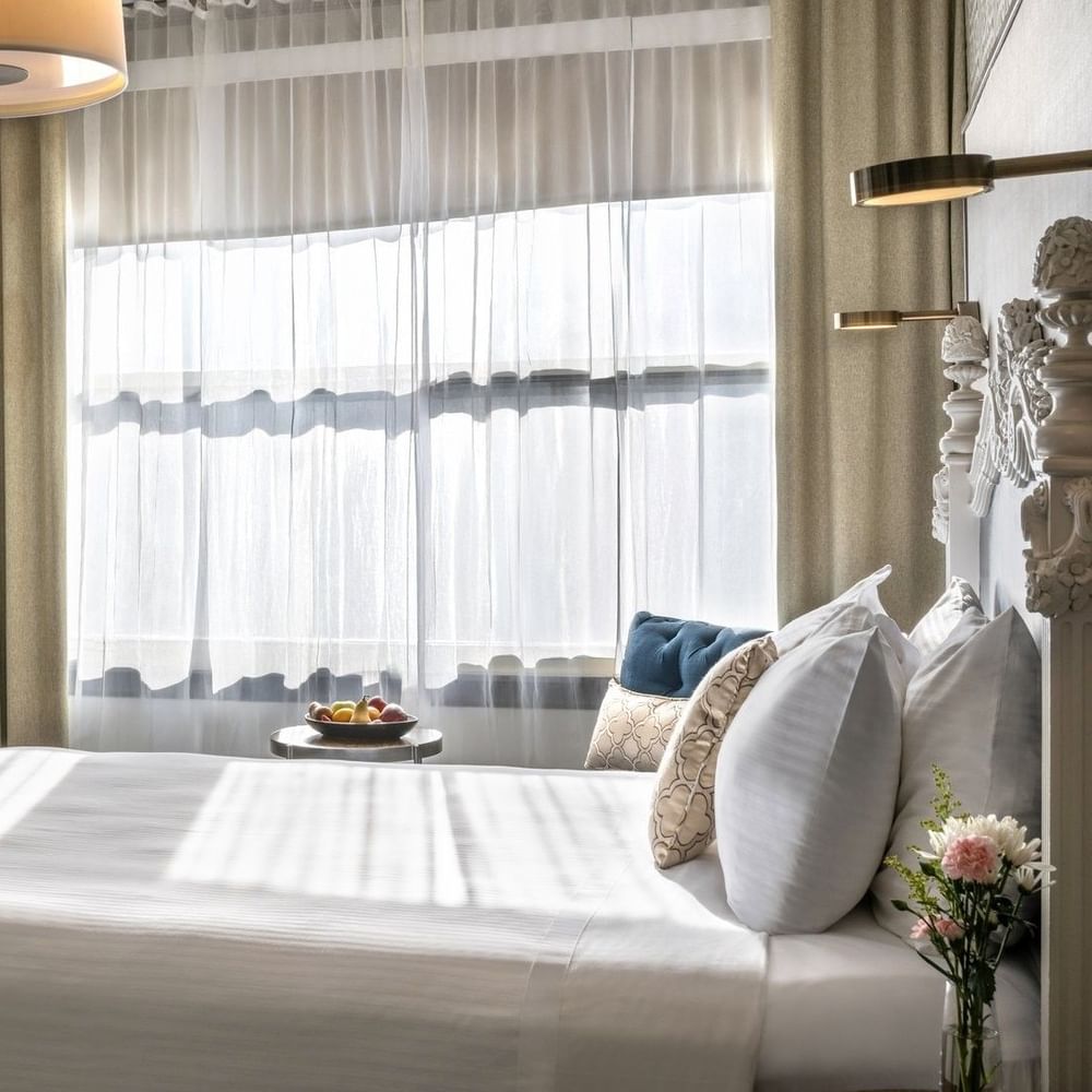Wooden desk and chair near windows with sheer curtains under a drum lamp in Corner Deluxe Room at Warwick San Francisco