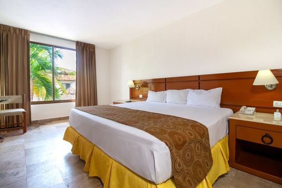 Comfy bed, bedside lamps & windows in a room at Plaza Pelicanos Club Beach Resort