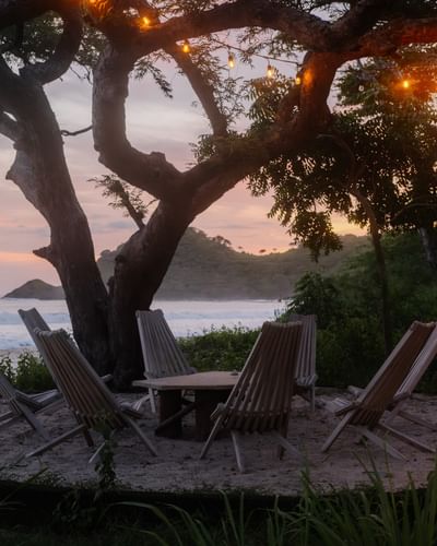 Evening beach scene with wooden chairs under glowing lights at Morgan’s Rock, one of the hotels in San Juan del Sur