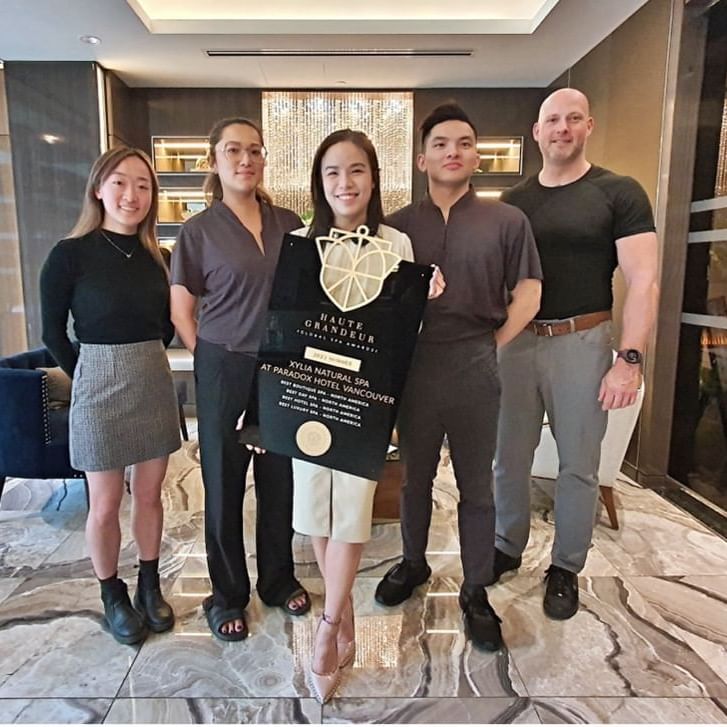 Staff members of the Xylia Spa stand together holding the plaque of the Haute Grandeur 2023 Global Spa Award.