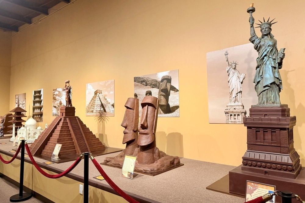 A roped off area displaying a variety of world monuments like the Easter Island statues and the Statue of Liberty made entirely from chocolate.