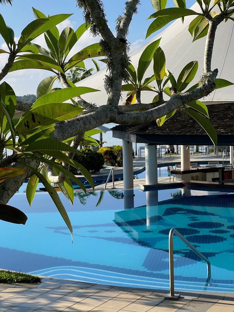 Sparkling pool by a pavilion under tropical leaves surrounding a tiled sun deck at Warwick Le Lagon - Vanuatu, Efate