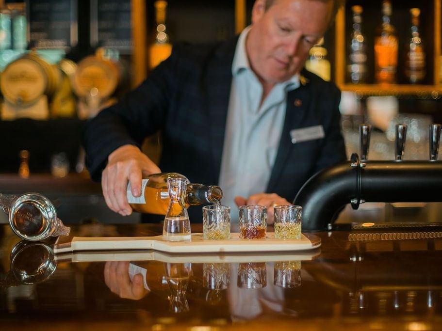 A man pouring whisky into glasses in the bar at Hotel Eldorado