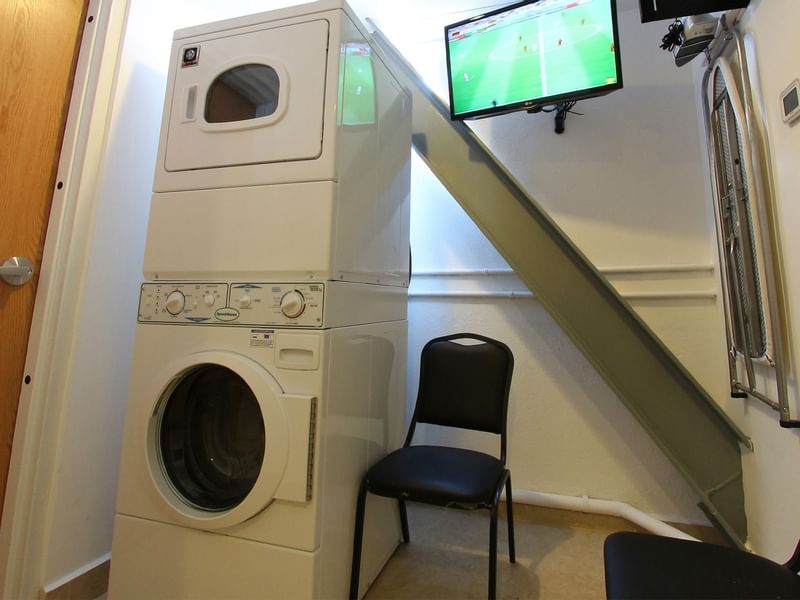 Washing machine & a wall TV in a laundry room at One Hotels