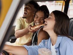 Friends enjoying pizza in the car near Hotel Factory Green