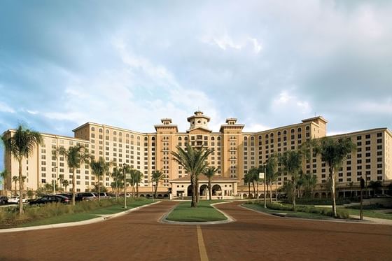Grand Rosen Shingle Creek exterior with main tower and lush palm-lined driveway under cloudy skies near Rosen Inn Hotels