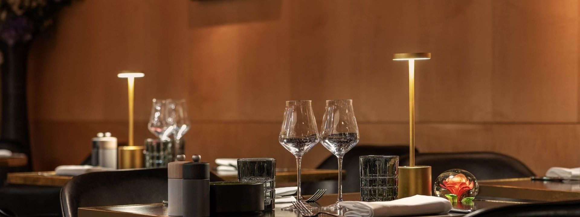 Une table élégamment dressée avec des verres à vin et de la vaisselle au restaurant « Le W » à Paris, au Warwick Paris.