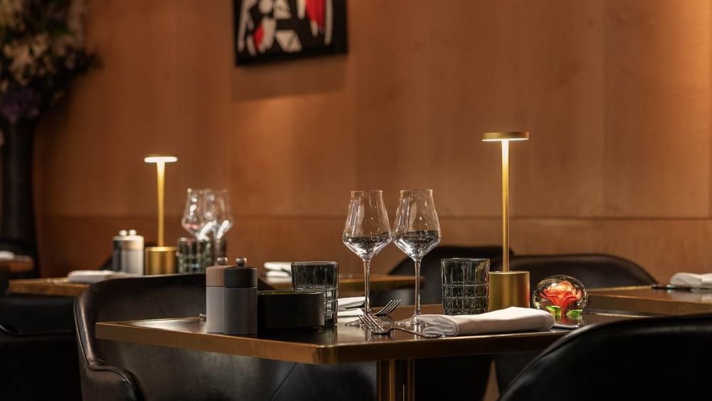Une table élégamment dressée avec des verres à vin et de la vaisselle au restaurant « Le W » à Paris, au Warwick Paris.