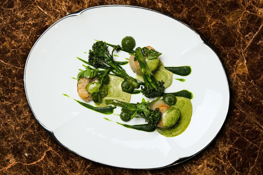 Gourmet dish with scallops, broccolini, and vibrant green sauces, elegantly presented in Square One at Park Hyatt Saigon